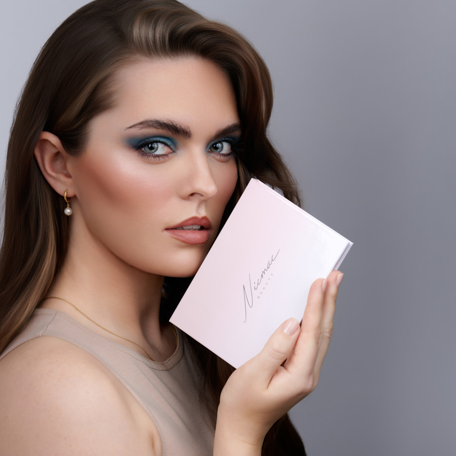 Model holding luxury beauty product packaging with soft studio lighting