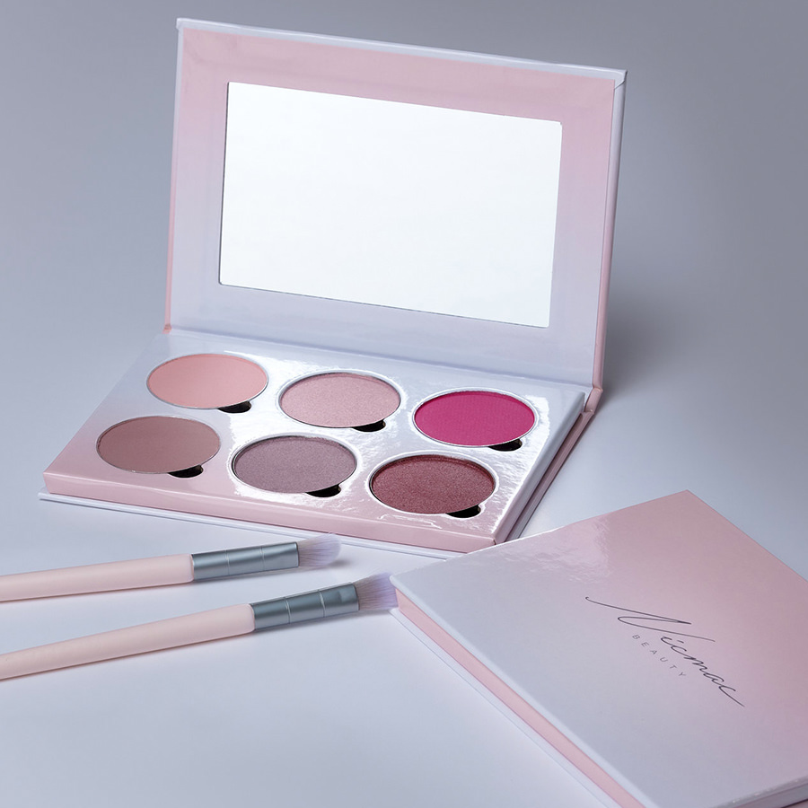 Nic Mac open pink eyeshadow palette with mirror and two makeup brushes on a grey background
